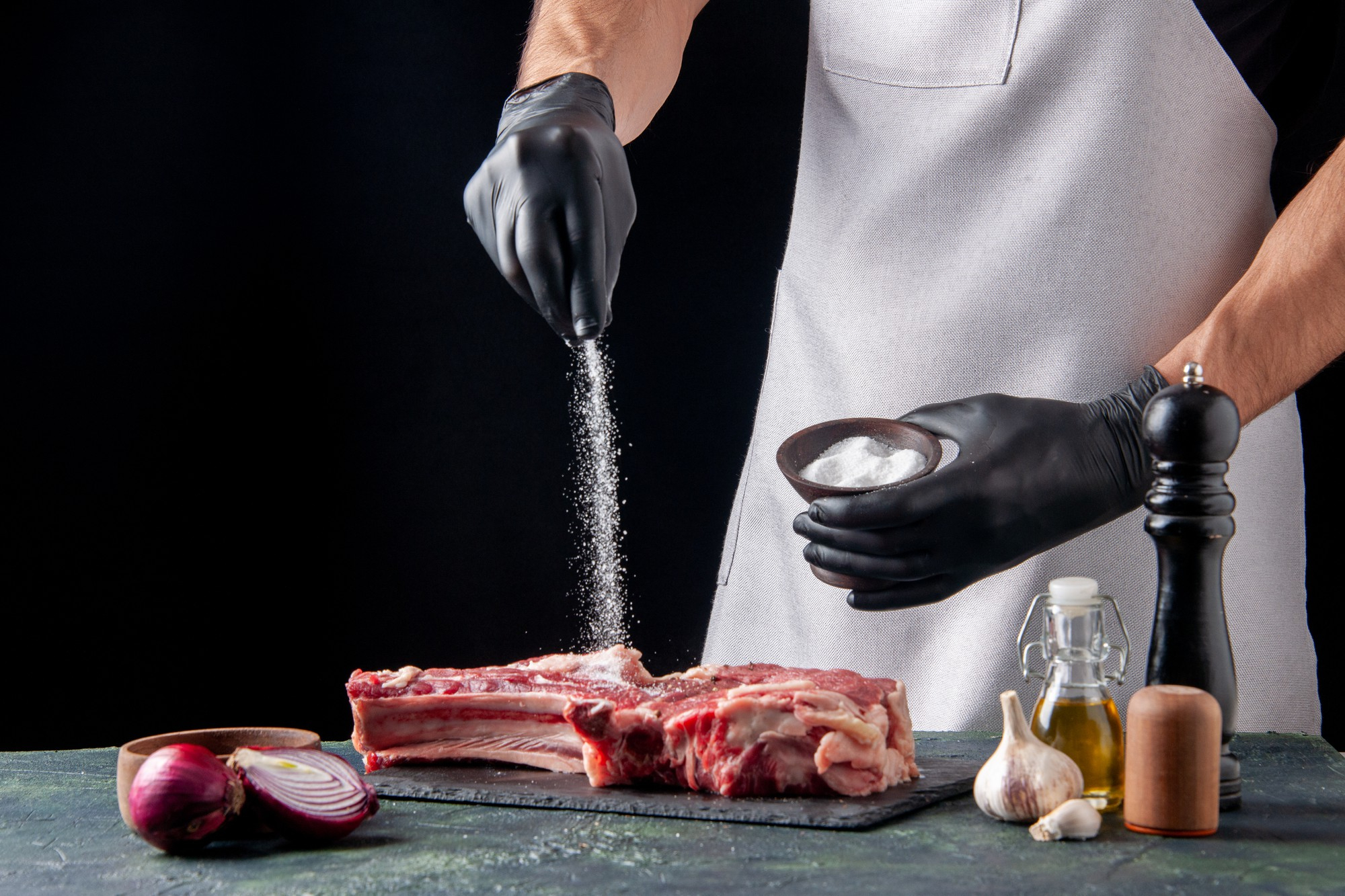 front-view-male-butcher-salting-meat-dark-surface