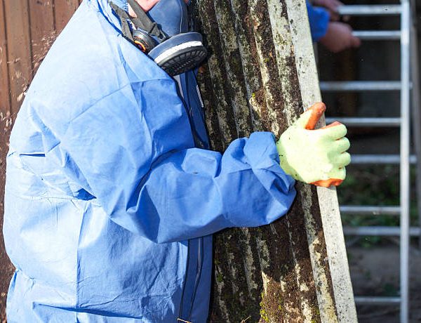 Asbestos corrugated roofing sheet being removed and sealed in a plastic sheet